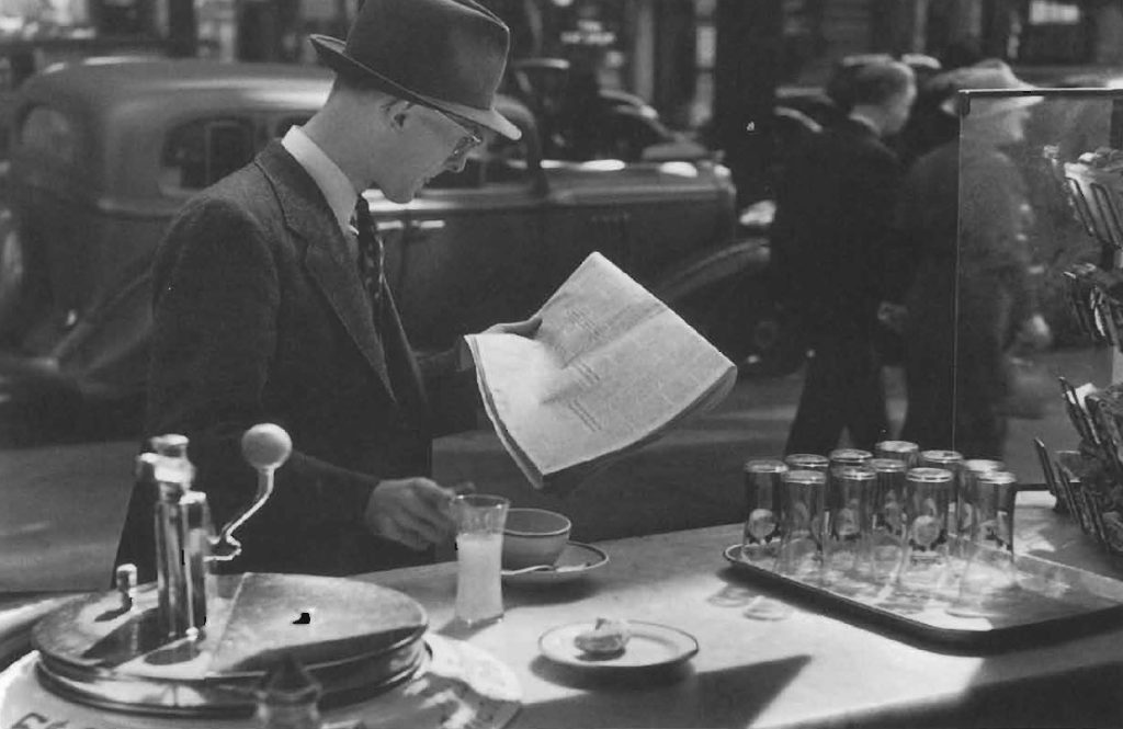 Petit déjeuner à l'américaine: café, jus de fruit, et lecture du journal au comptoir d'un étal de rue, vers 1949.